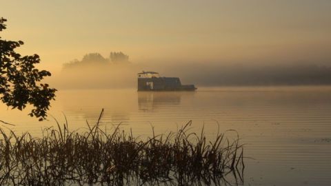 Sonnenaufgang auf dem See: mittendrin ein schwimmender Wohnwagen