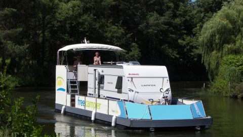 Ein freecamper mit Wohnwagen  schlängelt sich durch das Wassergebiet der Mecklenburgischen Seenplatte.